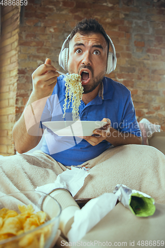 Image of Lazy man living the whole life in his bed surrounded with messy