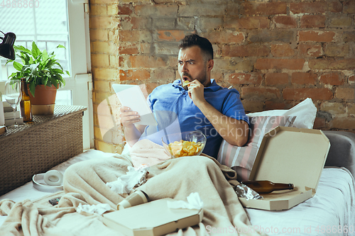 Image of Lazy man living the whole life in his bed surrounded with messy