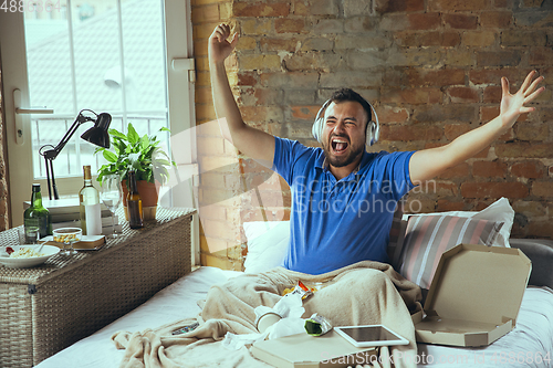 Image of Lazy man living the whole life in his bed surrounded with messy