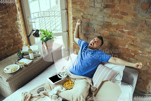 Image of Lazy man living the whole life in his bed surrounded with messy