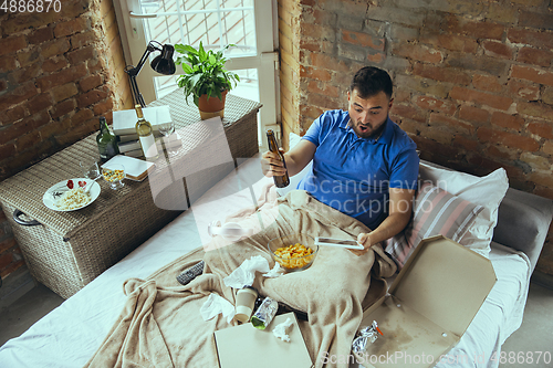Image of Lazy man living the whole life in his bed surrounded with messy