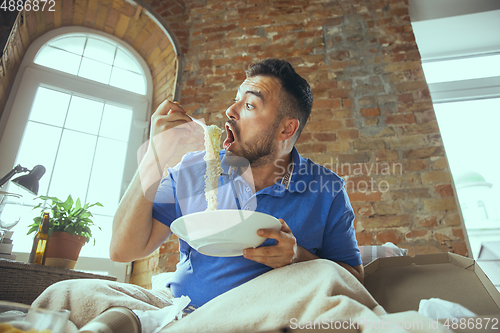 Image of Lazy man living the whole life in his bed surrounded with messy