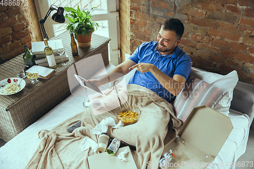 Image of Lazy man living the whole life in his bed surrounded with messy