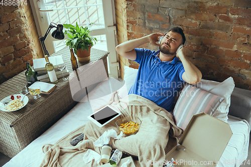 Image of Lazy man living the whole life in his bed surrounded with messy