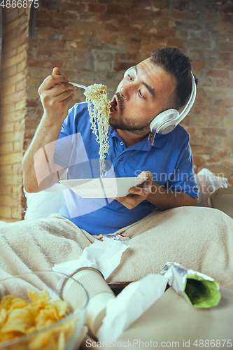 Image of Lazy man living the whole life in his bed surrounded with messy