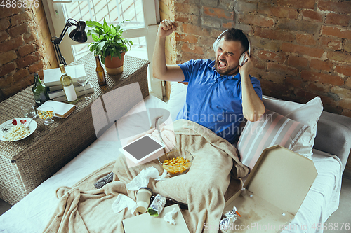 Image of Lazy man living the whole life in his bed surrounded with messy