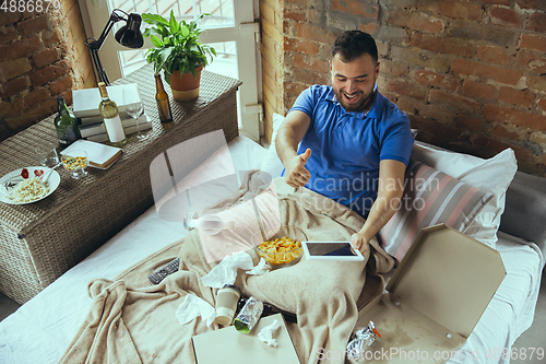 Image of Lazy man living the whole life in his bed surrounded with messy