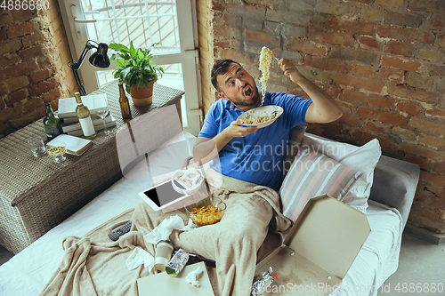 Image of Lazy man living the whole life in his bed surrounded with messy