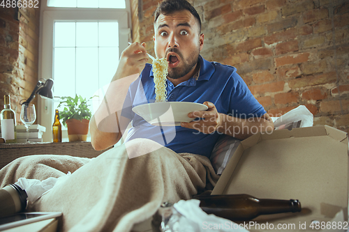 Image of Lazy man living the whole life in his bed surrounded with messy