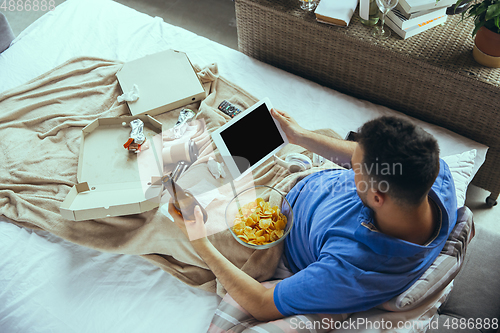 Image of Lazy man living the whole life in his bed surrounded with messy