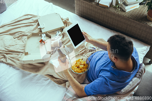 Image of Lazy man living the whole life in his bed surrounded with messy