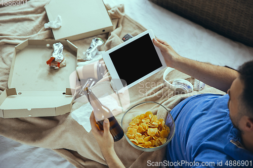 Image of Lazy man living the whole life in his bed surrounded with messy