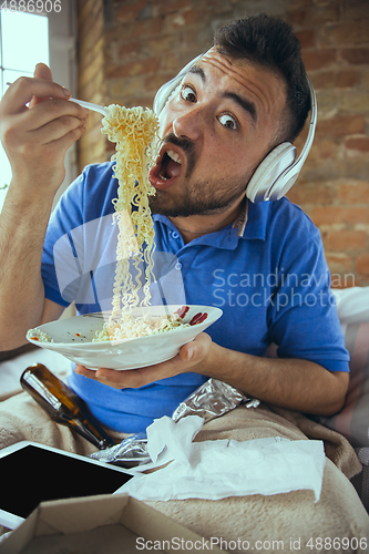 Image of Lazy man living the whole life in his bed surrounded with messy
