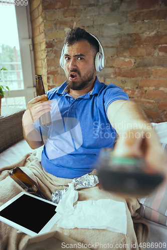 Image of Lazy man living the whole life in his bed surrounded with messy