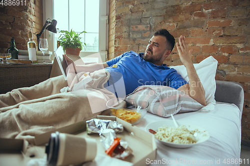 Image of Lazy man living the whole life in his bed surrounded with messy