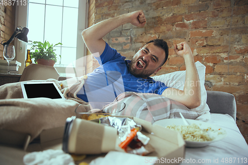 Image of Lazy man living the whole life in his bed surrounded with messy