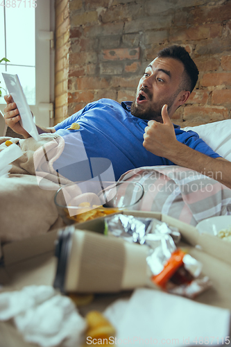 Image of Lazy man living the whole life in his bed surrounded with messy