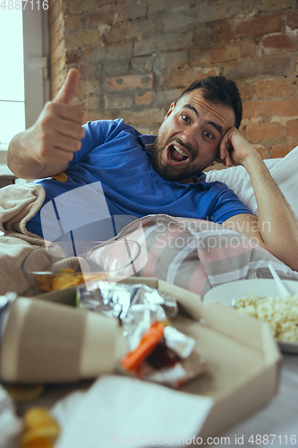 Image of Lazy man living the whole life in his bed surrounded with messy