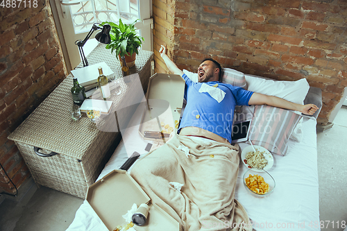 Image of Lazy man living the whole life in his bed surrounded with messy