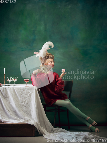 Image of Young woman as Marie Antoinette on dark background. Retro style, comparison of eras concept.