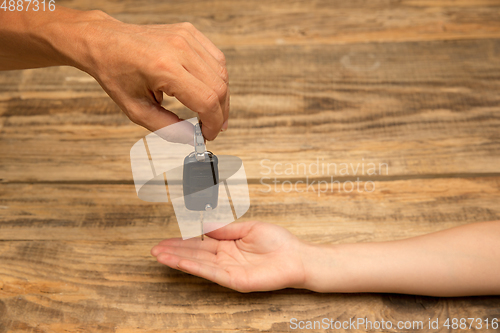 Image of Human hands holding car key isolated on wooden background with copyspace