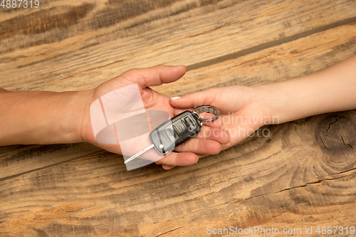 Image of Human hands holding car key isolated on wooden background with copyspace