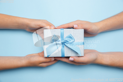 Image of Human\'s hands holding a present, gift, surprise box isolated on blue background