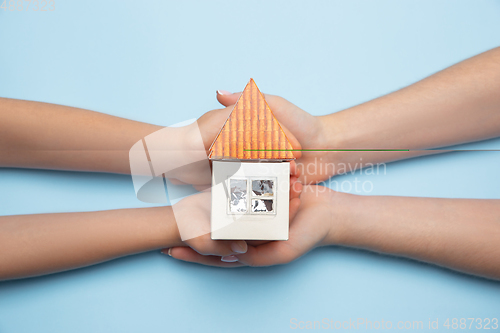 Image of Real estate and eco concept - close up picture of human hands holding house on blue background