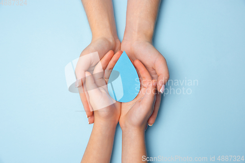 Image of Human hands holding water drop isolated on white wooden background