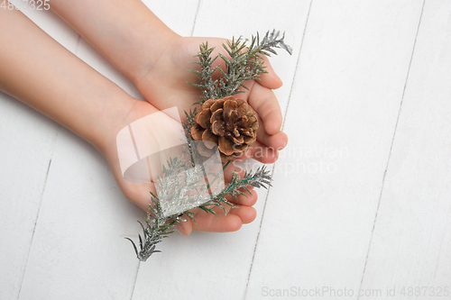 Image of Human\'s hand holding a Christmas decoration isolated on white wooden background