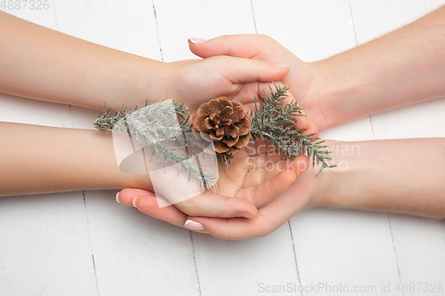 Image of Human\'s hand holding a Christmas decoration isolated on white wooden background