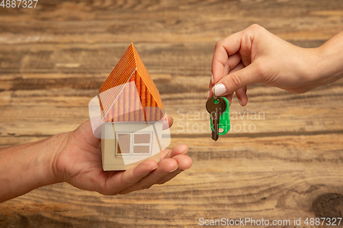 Image of Real estate and eco concept - close up picture of human hands holding house on wooden background