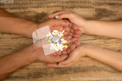 Image of Human hands holding bunch of pills isolated on wooden background with copyspace