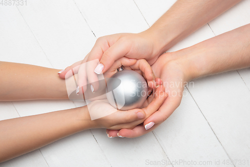Image of Human\'s hand holding a Christmas ball isolated on wooden white background