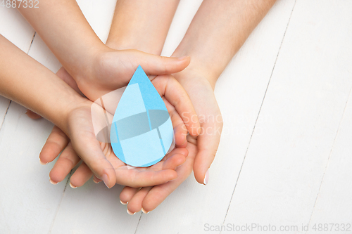 Image of Human hands holding water drop isolated on white wooden background