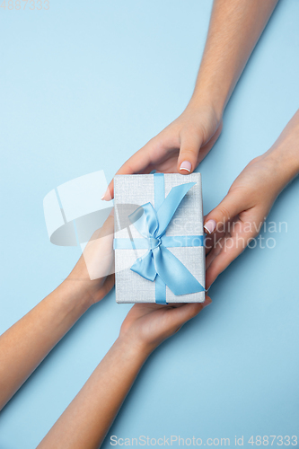 Image of Human\'s hands holding a present, gift, surprise box isolated on blue background