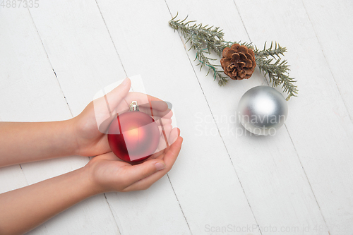 Image of Human\'s hand holding a Christmas ball isolated on wooden white background