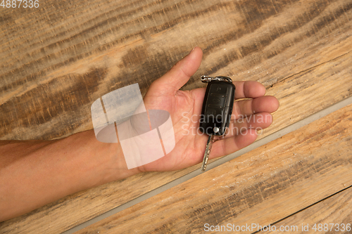 Image of Human hands holding car key isolated on wooden background with copyspace