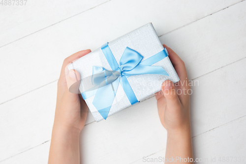 Image of Human\'s hands holding a present, gift, surprise box isolated on white wooden background
