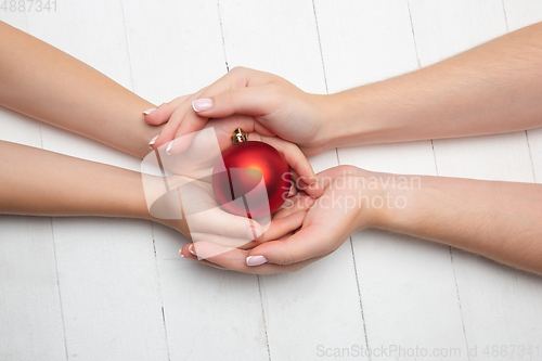 Image of Human\'s hand holding a Christmas ball isolated on wooden white background