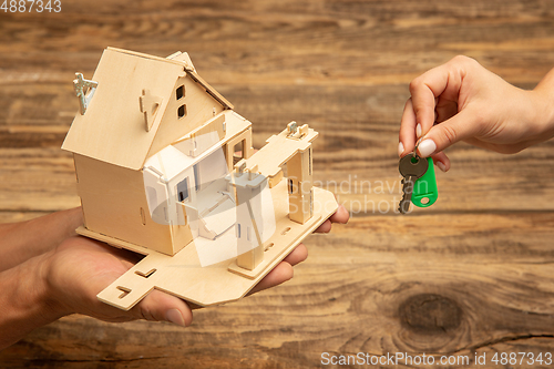 Image of Real estate and eco concept - close up picture of human hands holding house on wooden background