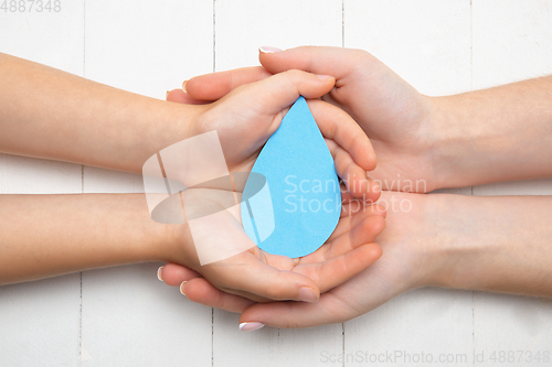Image of Human hands holding water drop isolated on white wooden background