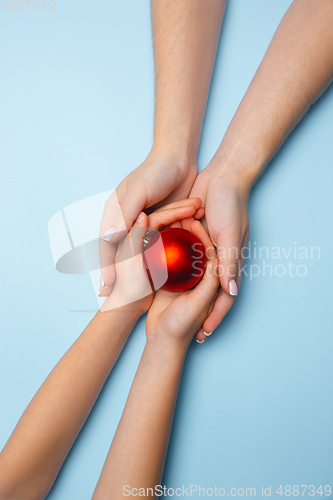 Image of Human\'s hand holding a Christmas ball isolated on blue background