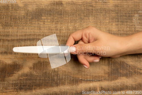 Image of Human hand holding thermometer isolated on wooden background