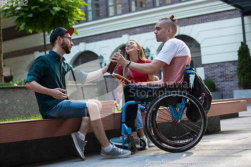 Image of Group of friends taking a stroll on city\'s street in summer day