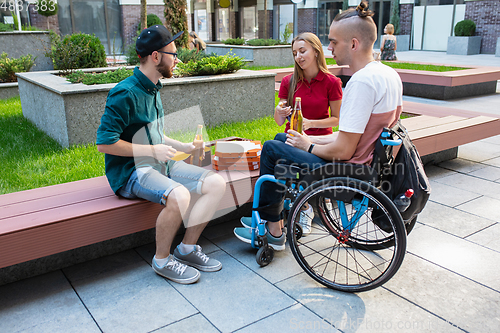 Image of Group of friends taking a stroll on city\'s street in summer day