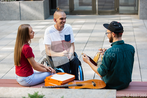 Image of Group of friends taking a stroll on city\'s street in summer day