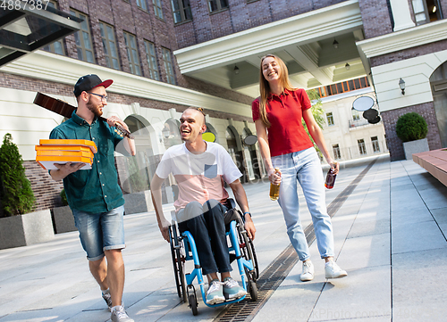 Image of Group of friends taking a stroll on city\'s street in summer day