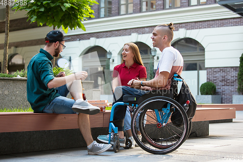 Image of Group of friends taking a stroll on city\'s street in summer day