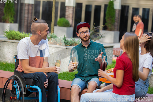 Image of Group of friends taking a stroll on city\'s street in summer day